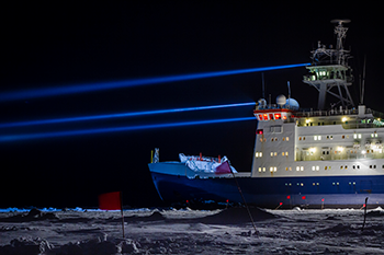 an image of a brightly lit ice-locked research vessel at night