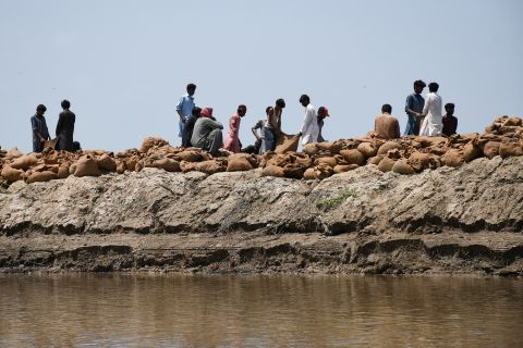 People prepare sandbags to build a barrier to stop the floodwaters in Puran Dhoro, Pakistan, on August 30.